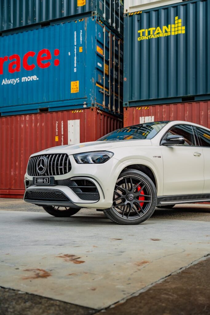 A sleek white Mercedes SUV parked next to colorful shipping containers in Sydney, Australia.